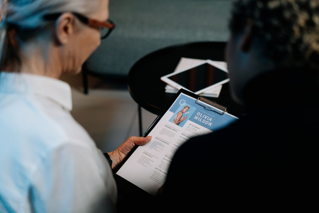 Professionals discussing a resume on a clipboard.