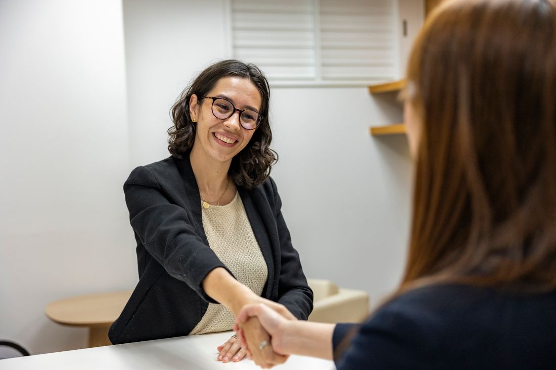 Two businesswomen shaking hands during an interview.